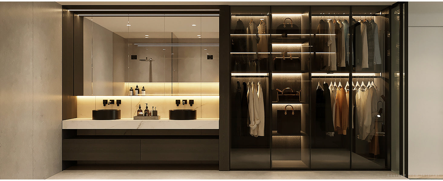 A modern bathroom and wardrobe space with warm LED lighting, featuring a sink area and a glass-enclosed closet with neatly arranged clothes and shelves.
